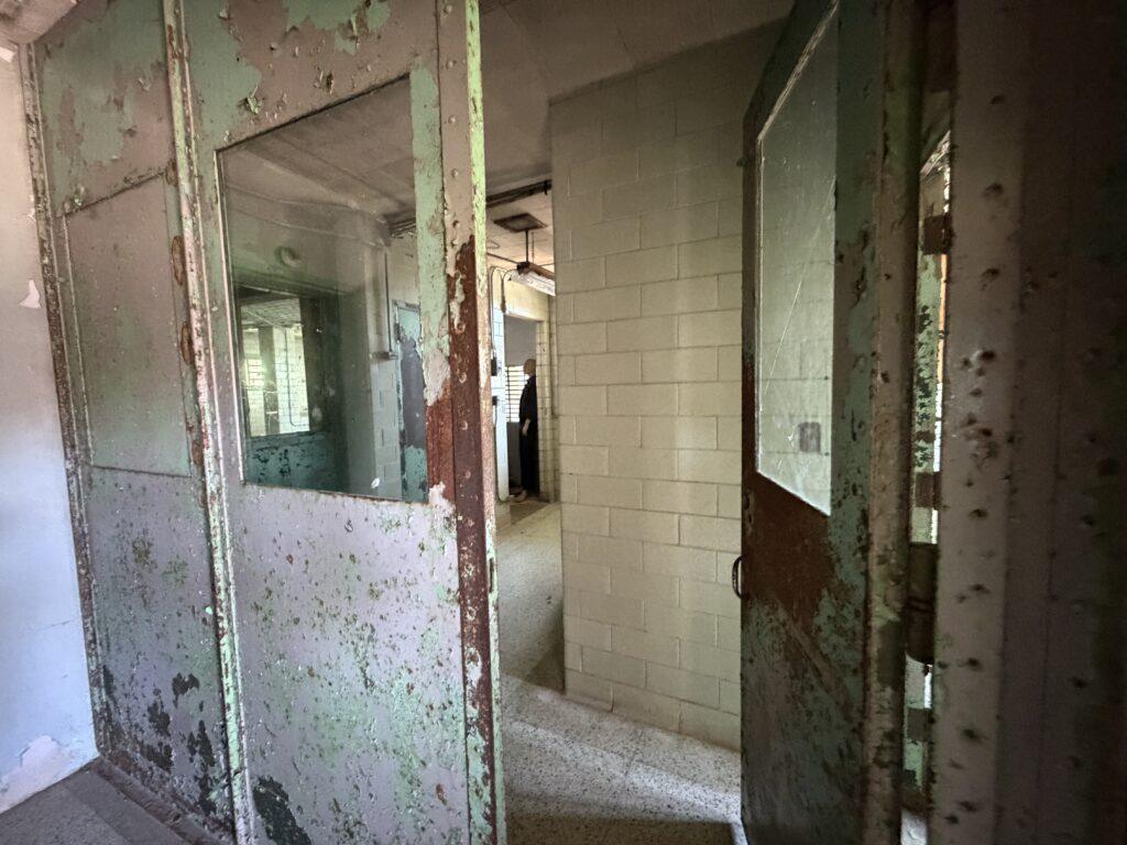 Peeling green doors and interior corridor inside the forensic building at Trans-Allegheny Lunatic Asylum