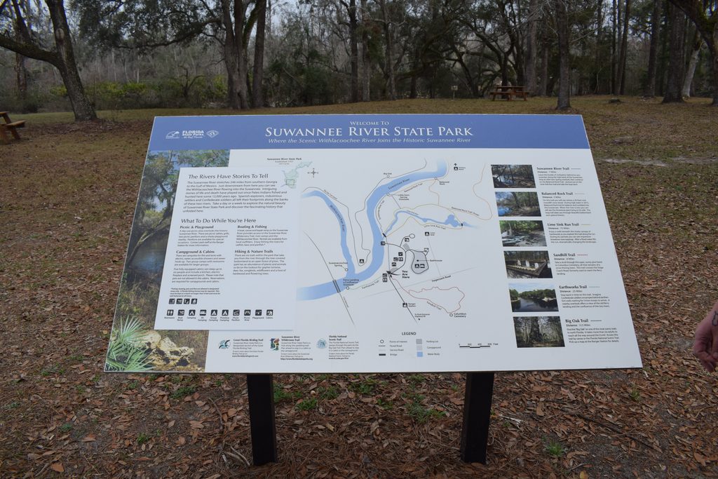 Large illustrated trail map at Suwannee River State Park showing the Suwannee and Withlacoochee Rivers, hiking trails, Columbus Cemetery, and park attractions.