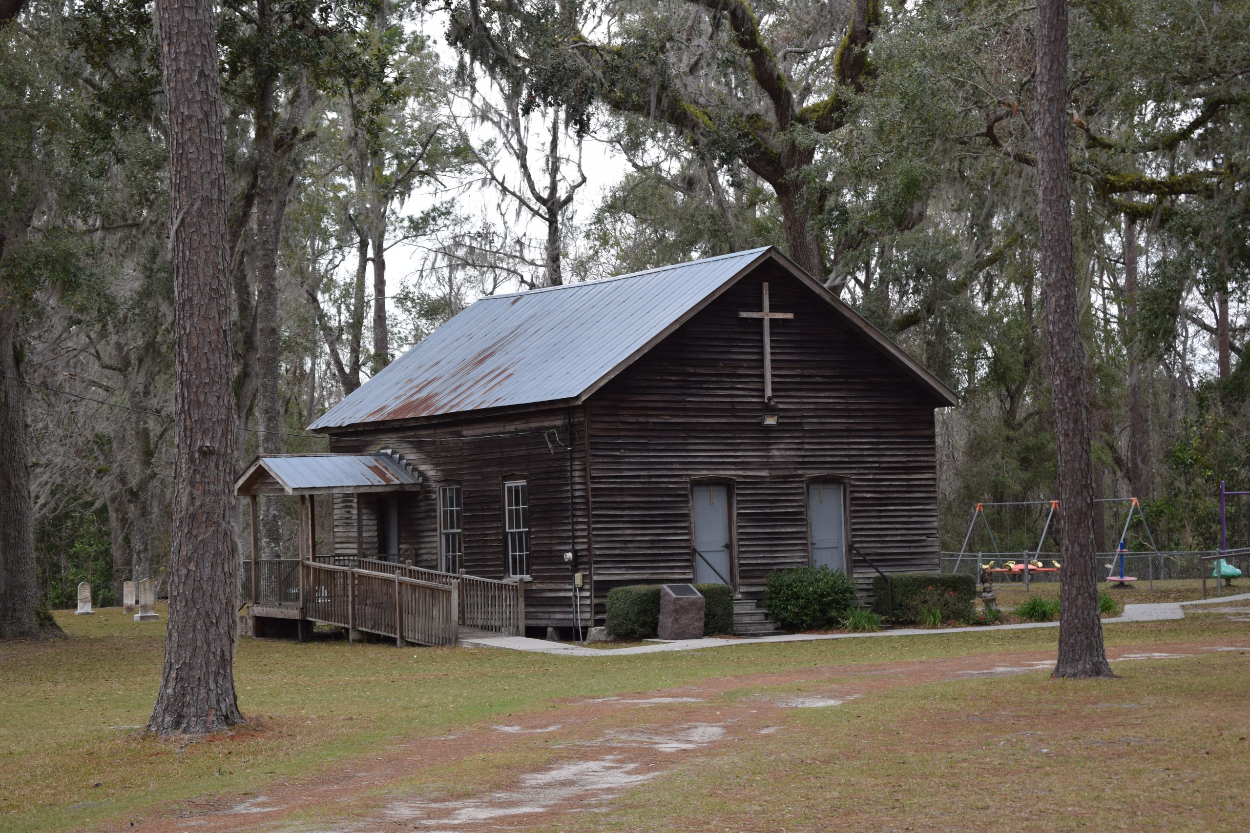 Historic wooden Falling Creek Methodist Church surrounded by oak and pine trees near Lake City, Florida