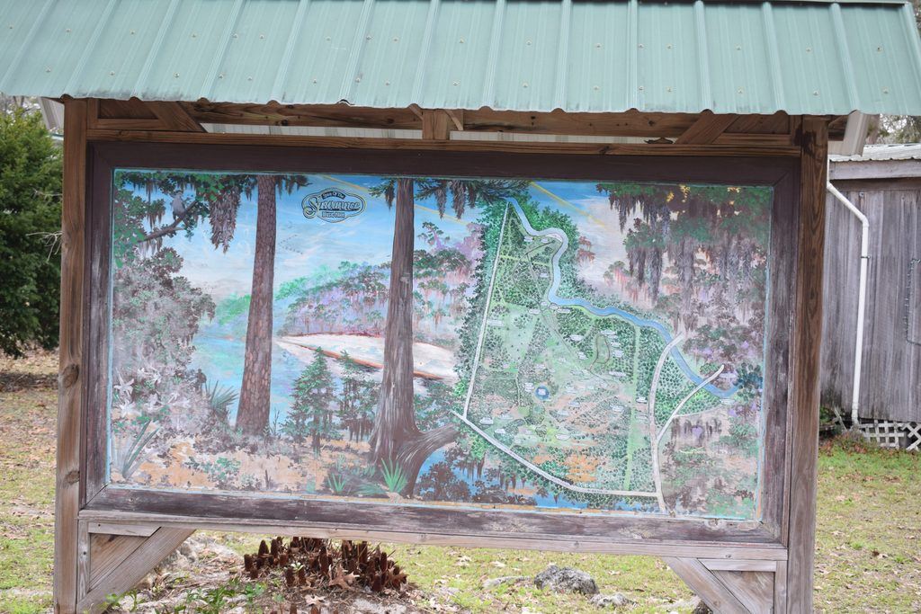 Illustrated map of Spirit of the Suwannee Music Park displayed beneath a wooden shelter, showing the campground, wooded landscape, and winding Suwannee River in Live Oak, Florida.