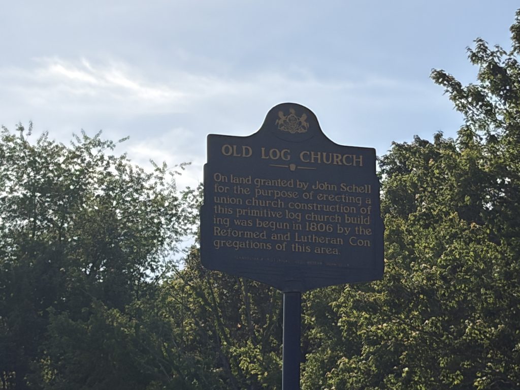 Pennsylvania historical marker identifying the Old Log Church, built in 1806 by German Reformed and Lutheran congregations on land donated by John Schell in Bedford County.