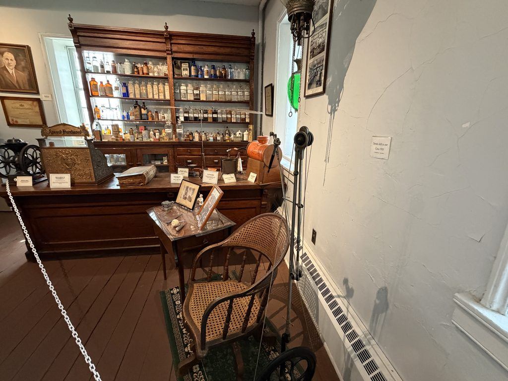 Historic medical exhibit inside the Old Franklin County Jail Museum in Chambersburg, Pennsylvania, featuring antique medicine bottles, wooden cabinets, medical instruments, and a vintage examination chair.