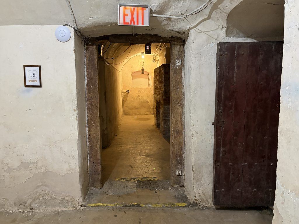 White circular Wi-Fi access point mounted beside an illuminated EXIT sign above a doorway leading into the underground dungeon at the Old Franklin County Jail in Chambersburg, Pennsylvania.