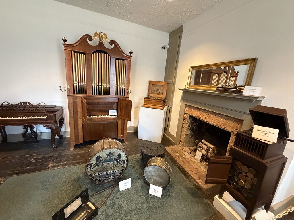 Historic musical instruments exhibit at the Franklin County Historical Society Museum in Chambersburg, Pennsylvania, featuring an antique pipe organ, piano, drums, accordion, and Edison cylinder player.