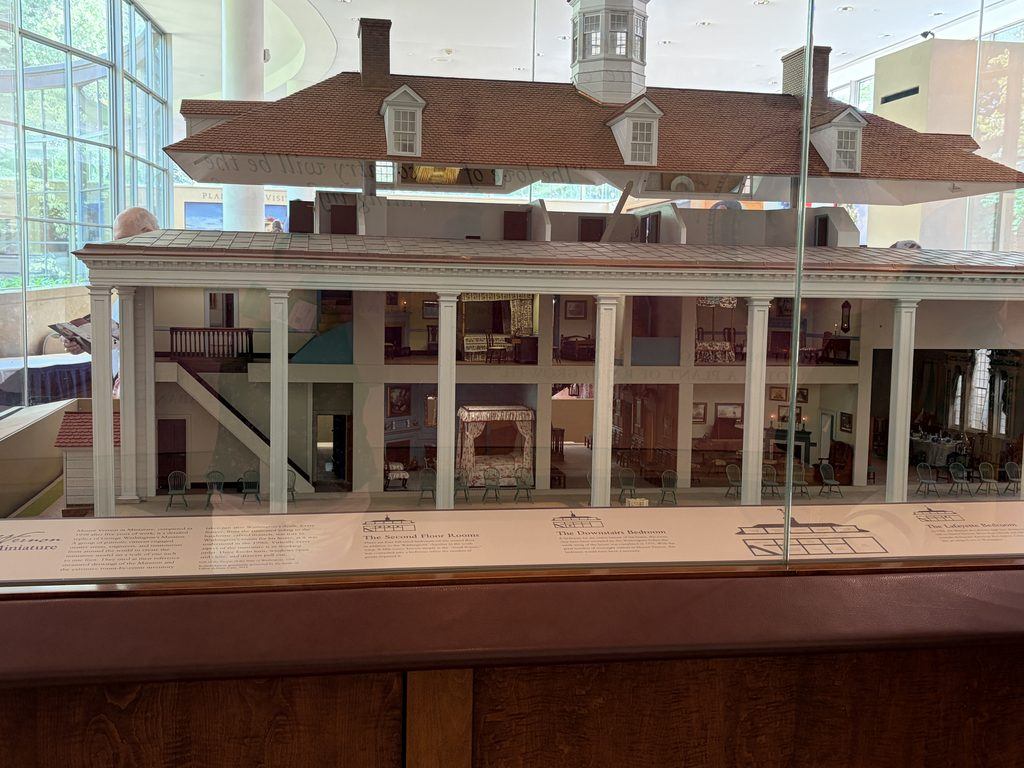 Architectural cutaway model of George Washington’s Mount Vernon mansion displayed in the visitor center, revealing furnished rooms, staircases, bedrooms, and the mansion’s interior layout.