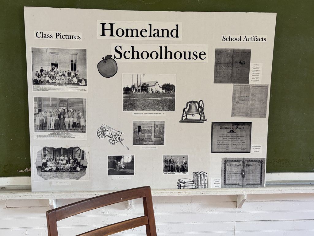 Homeland Schoolhouse historical display featuring vintage class photographs, images of the 1878 school building, school records, and student certificates inside Homeland Heritage Park in Polk County, Florida.